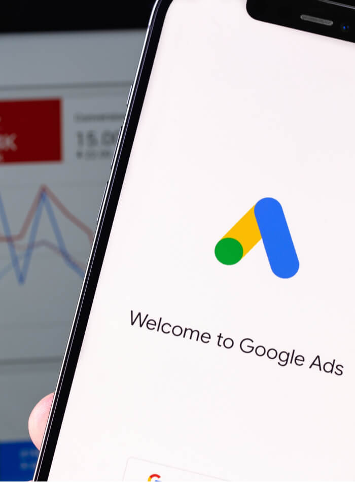 a person holding a cell phone with google ads on the screen.